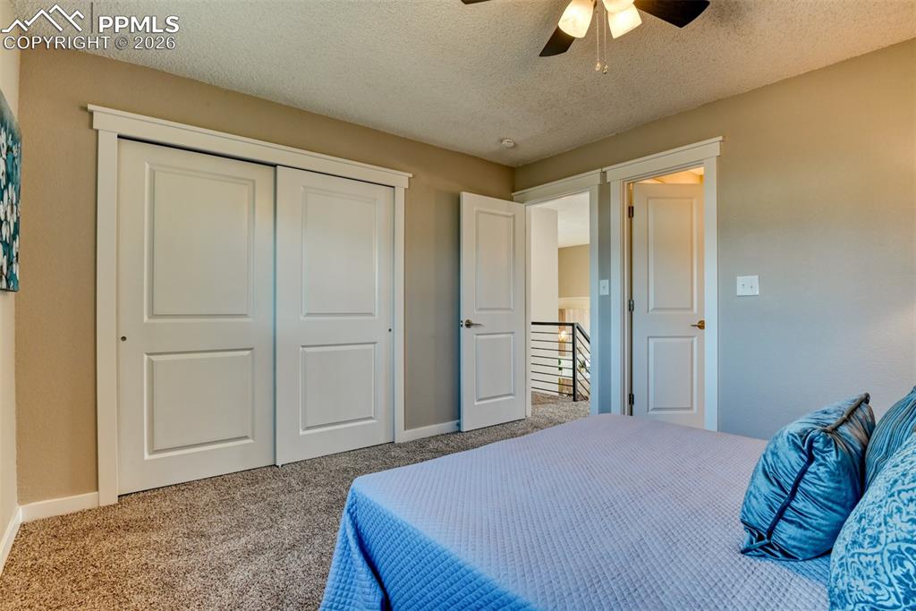 Image 21 of 44: Carpeted bedroom with a textured ceiling, a closet, and ceiling fan