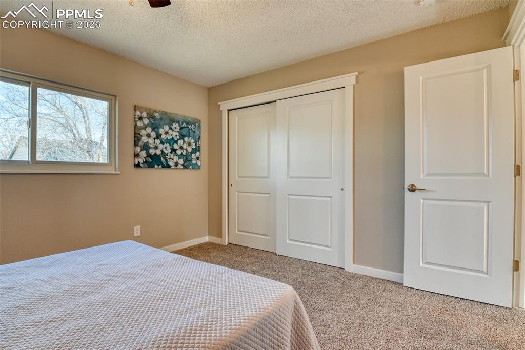 Image 22 of 44: Bedroom with carpet, a textured ceiling, a closet, and a ceiling fan