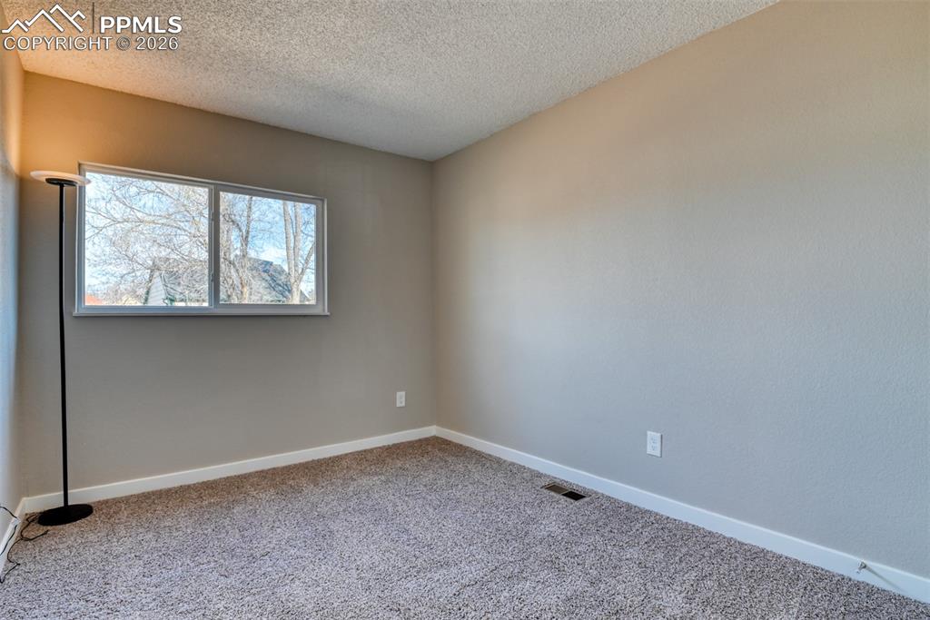 Image 25 of 44: Empty room featuring light colored carpet and a textured ceiling