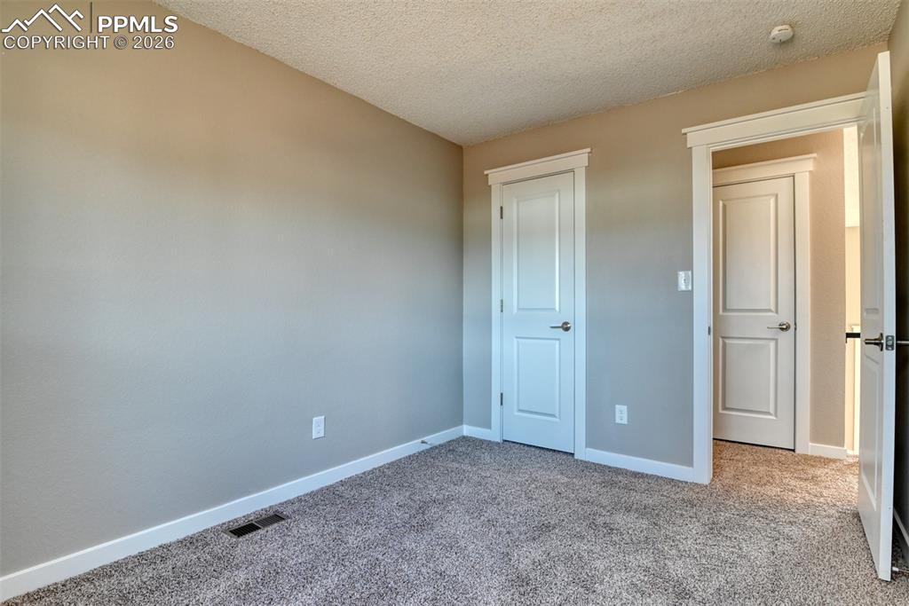 Image 28 of 44: Unfurnished bedroom with carpet flooring, a textured ceiling, and a closet