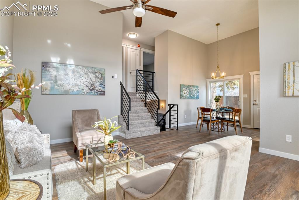 Image 6 of 44: Living area with a high ceiling, a ceiling fan, wood finished floors, and s