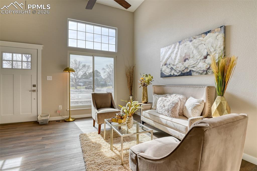 Image 9 of 44: Living room featuring a high ceiling, ceiling fan, and wood finished floors