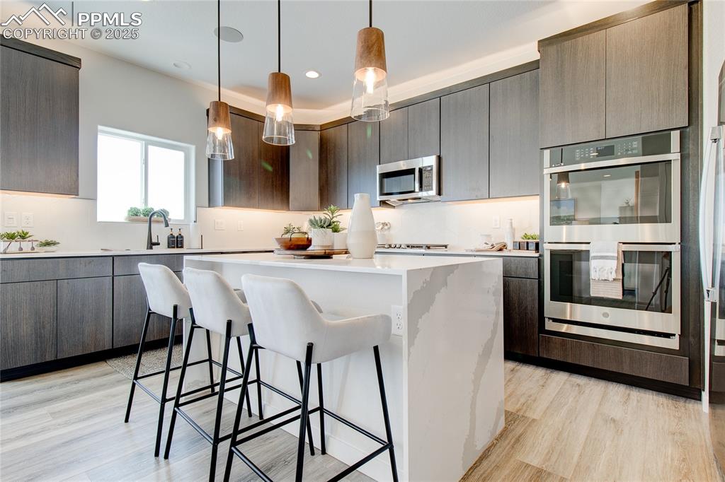 Image 16 of 32: Kitchen featuring a kitchen breakfast bar, stainless steel appliances, hang