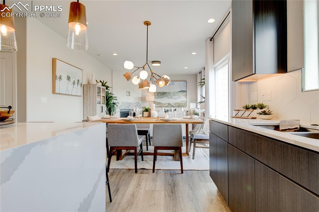 Image 19 of 32: Kitchen featuring decorative light fixtures, light wood finished floors, ba