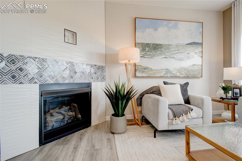 Image 26 of 32: Living area featuring wood finished floors and a tiled fireplace