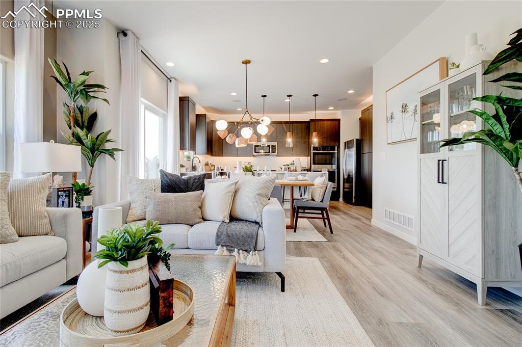 Image 28 of 32: Living room with light wood-type flooring, a chandelier, and recessed light