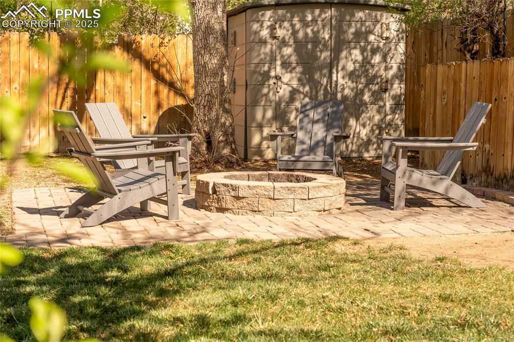 Image 38 of 42: View of yard featuring a patio, a fire pit, and a storage unit