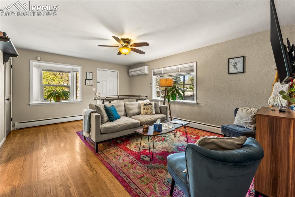 Image 4 of 42: Living area featuring a textured wall, wood finished floors, a baseboard he