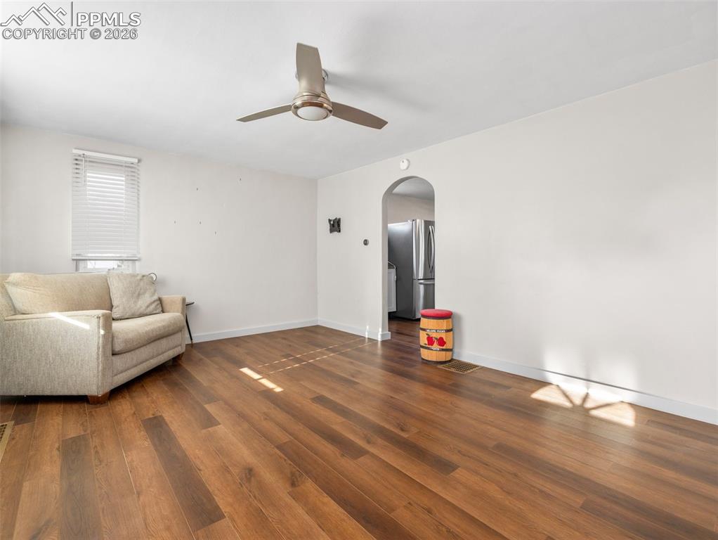 Image 3 of 10: Living area with arched walkways, dark wood finished floors, and ceiling fa