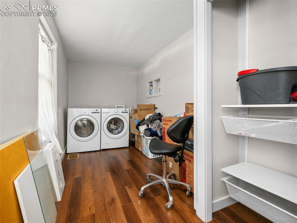 Image 5 of 10: Laundry area with dark wood-style floors and independent washer and dryer