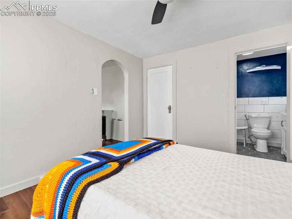 Image 7 of 10: Bedroom featuring arched walkways, ceiling fan, and tile walls