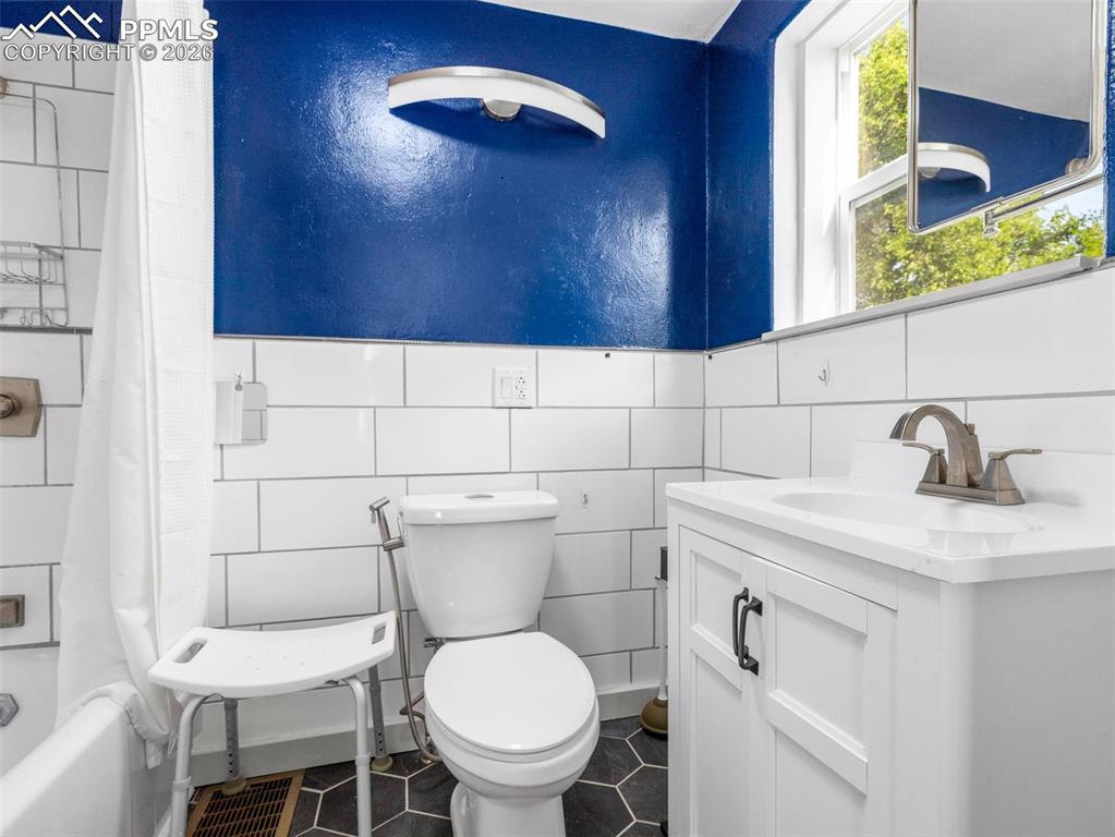 Image 8 of 10: Bathroom with vanity, shower / bath combo, and tile walls