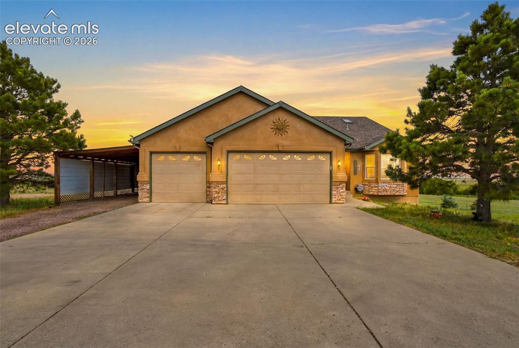 Caption: Siding exterior with stone accents, three-car garage, concrete driveway, and covered carport