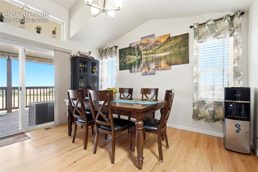 Image 11 of 44: Bright dining area with wood-finish flooring, vaulted ceilings with skyligh