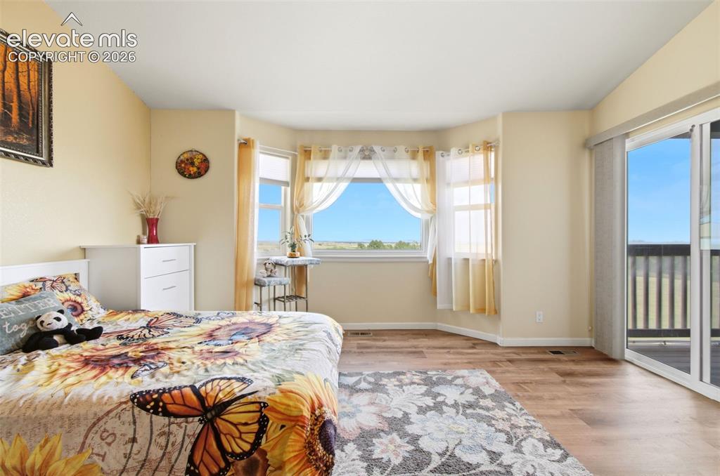 Image 13 of 44: Bright, sun-filled primary bedroom featuring glass sliding door access to b