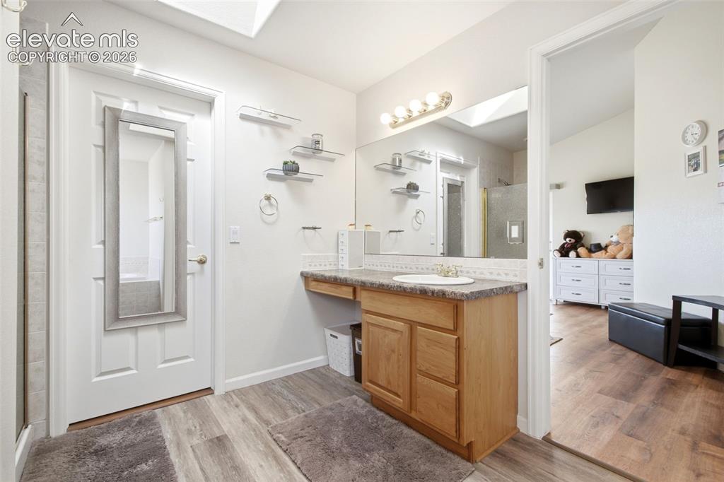 Image 19 of 44: Master bathroom featuring a wood-finish vanity with ample storage, granite 
