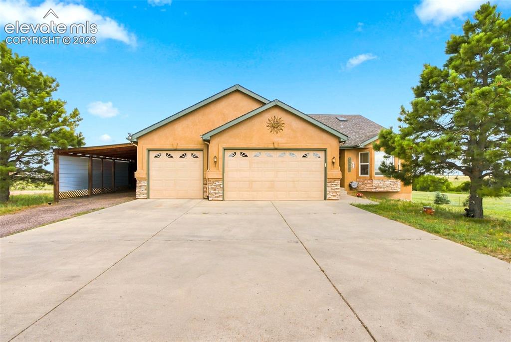 Image 2 of 44: Spacious driveway with concrete surface leading to a three-car garage