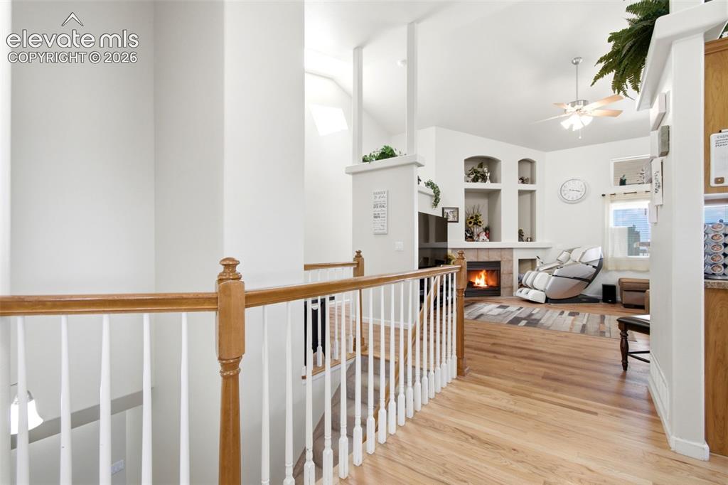 Image 20 of 44: Hallway featuring a vaulted ceiling, built-in fireplace, recessed shelving,