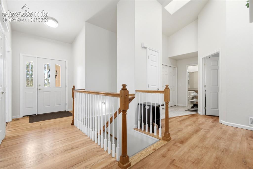 Image 21 of 44: Entryway featuring wood-finish flooring, a white spindle staircase, and a d
