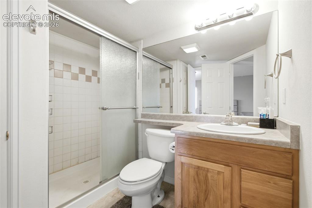 Image 29 of 44: Shower with sliding glass doors, white tiled walls, and a checkered accent 