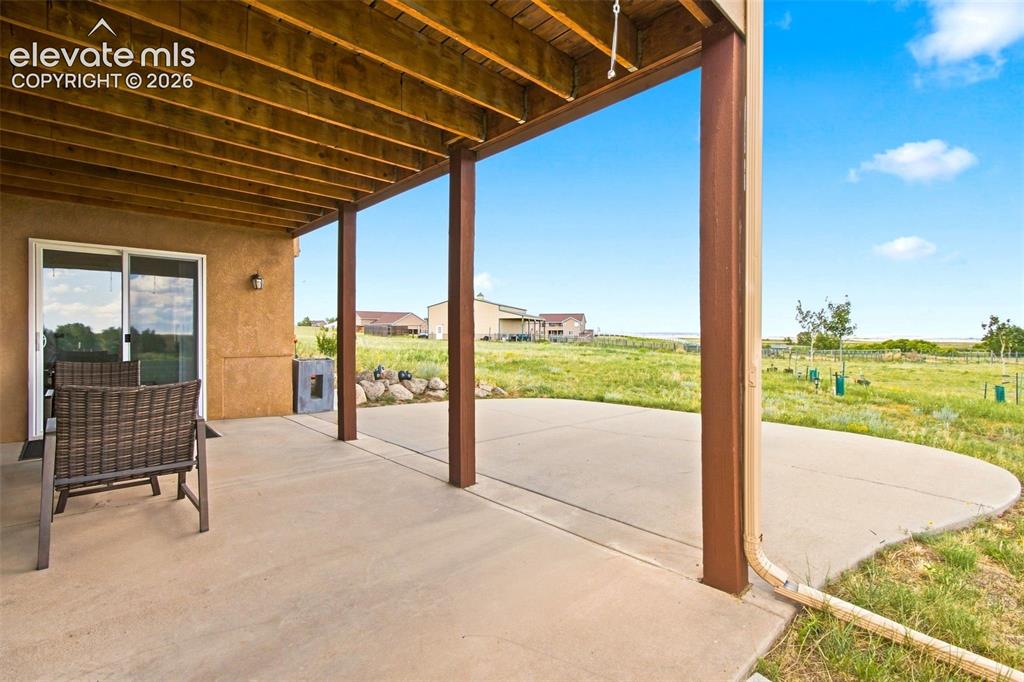 Image 31 of 44: Expansive covered patio with wood-beam ceiling and structural steel support
