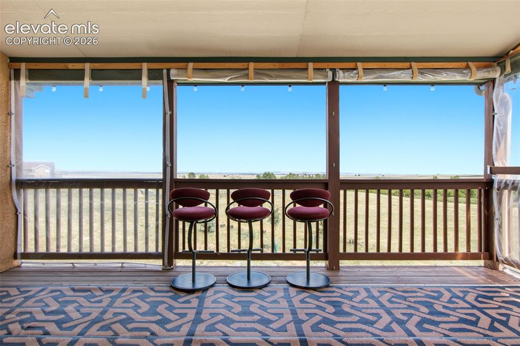Image 44 of 44: Covered outdoor deck with wood-finish flooring and railing
