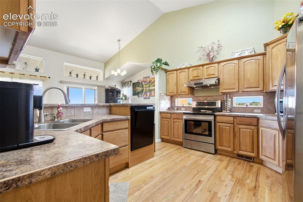 Image 6 of 44: Kitchen with vaulted ceilings, wood-finish flooring, stainless steel applia