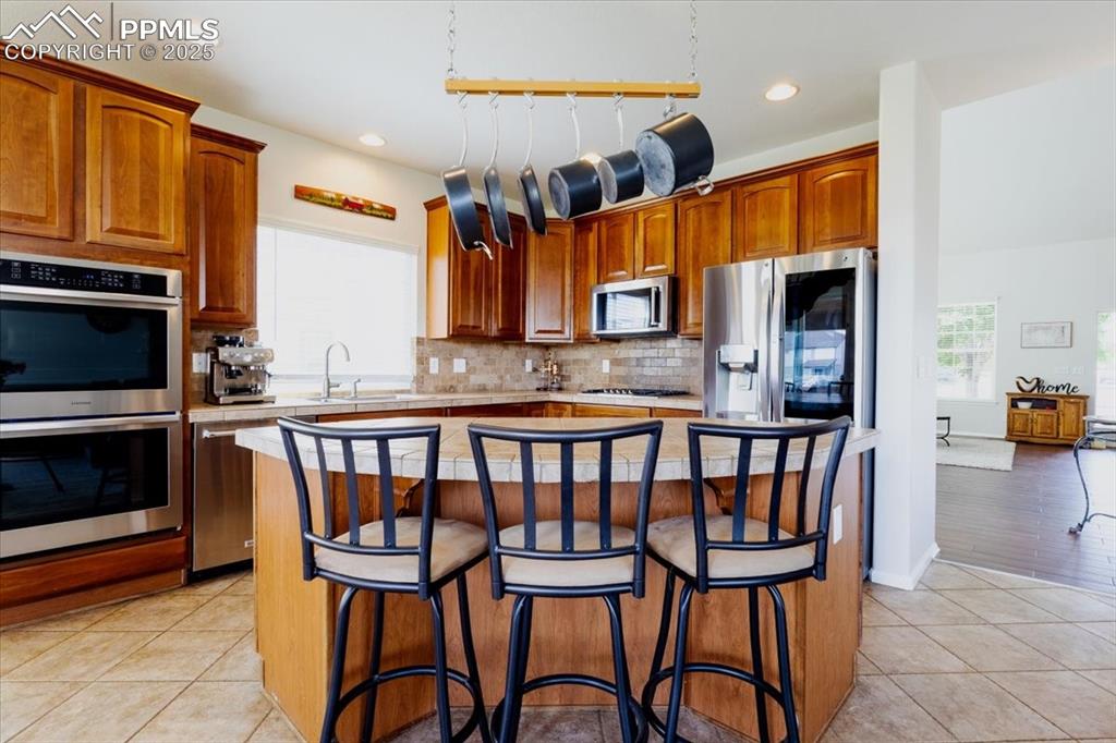 Image 10 of 30: Kitchen featuring a breakfast bar, appliances with stainless steel finishes