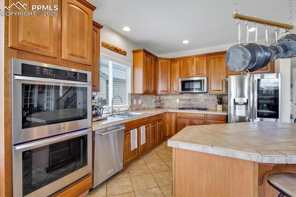 Image 14 of 30: Kitchen featuring appliances with stainless steel finishes, decorative back