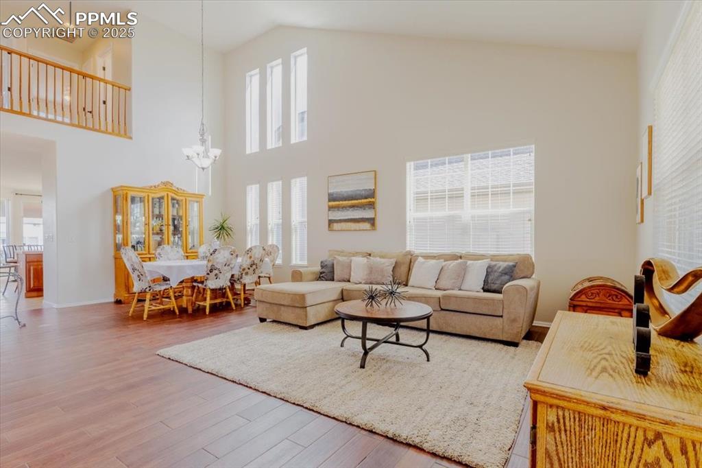 Image 2 of 30: Living room with high vaulted ceiling, wood finished floors, and a chandeli