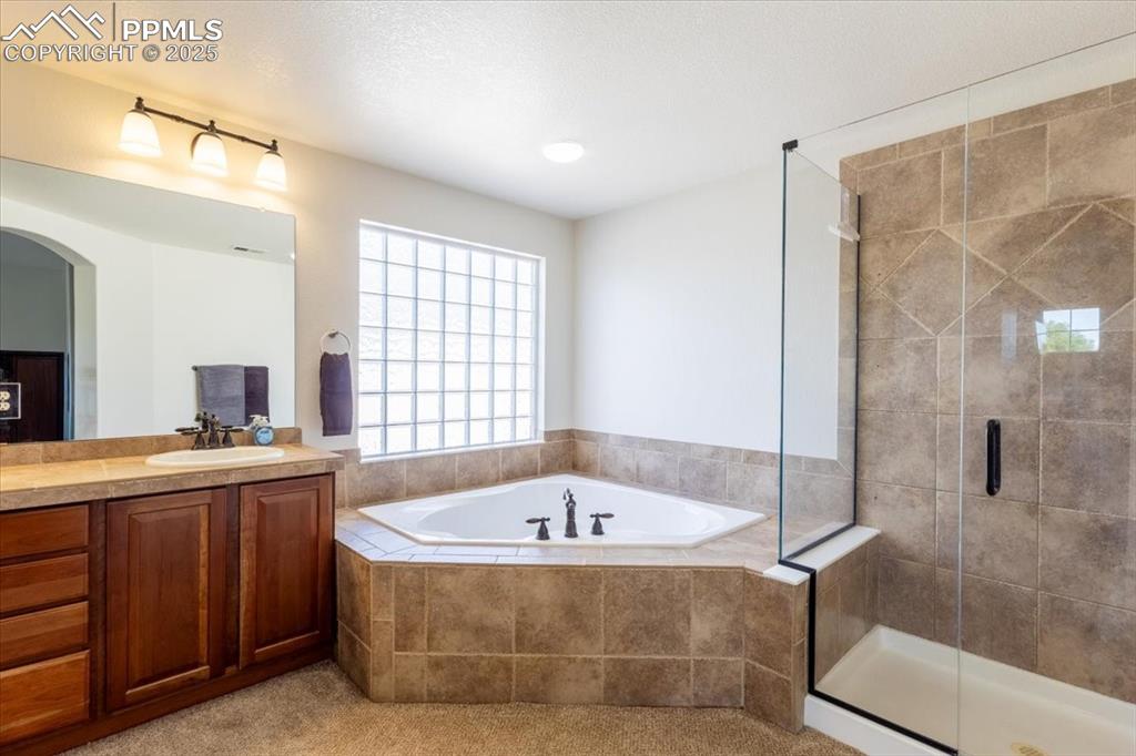 Image 20 of 30: Bathroom featuring a bath, vanity, and a shower stall