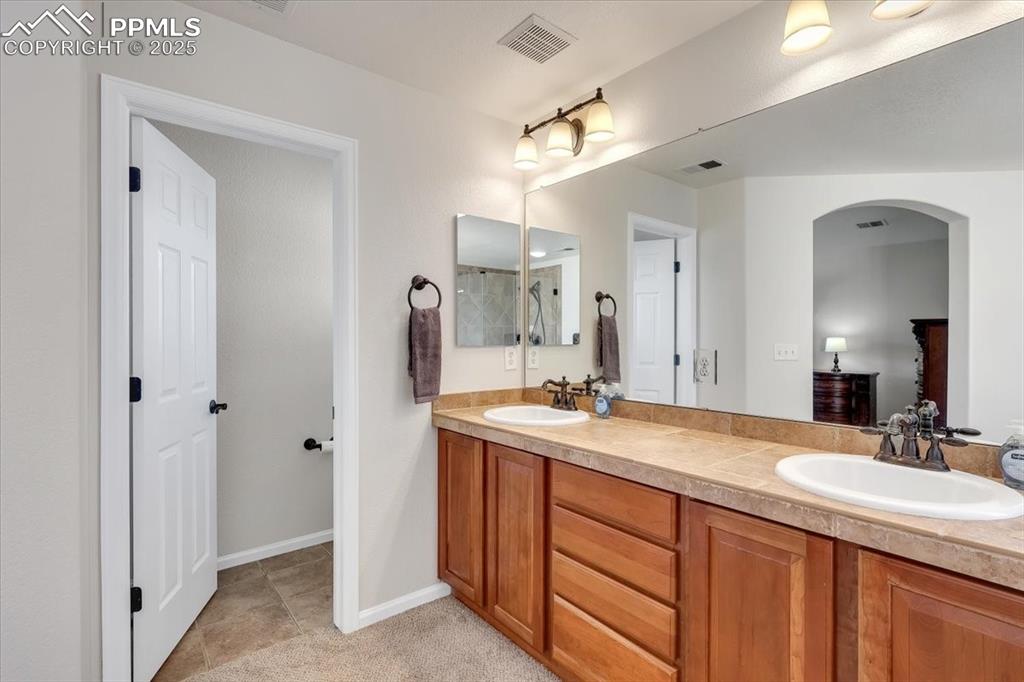 Image 21 of 30: Bathroom featuring double vanity and light tile patterned floors