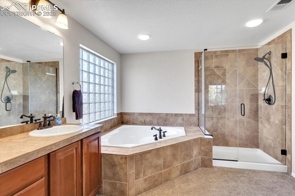 Image 22 of 30: Bathroom featuring a shower stall, a garden tub, vanity, and a textured cei