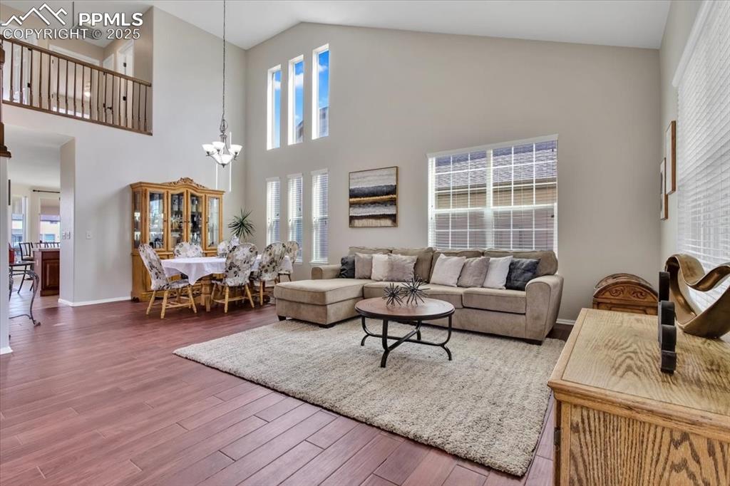 Image 4 of 30: Living room featuring high vaulted ceiling, wood finished floors, and a cha