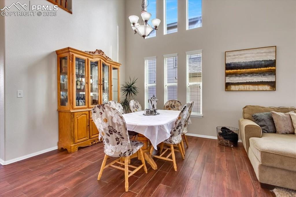 Image 5 of 30: Dining room featuring dark wood-type flooring, a towering ceiling, and a ch