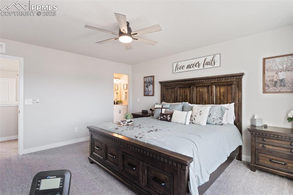 Image 13 of 26: Bedroom featuring light colored carpet, ceiling fan, and ensuite bath