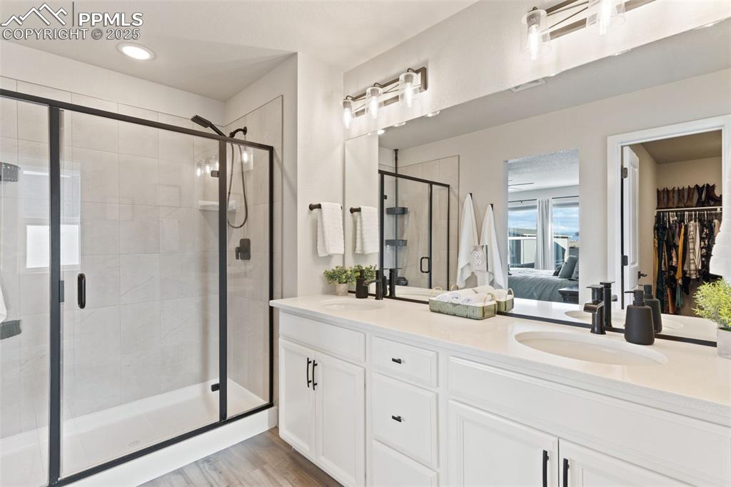 Image 14 of 26: Ensuite bathroom featuring a stall shower, double vanity, light wood-type f
