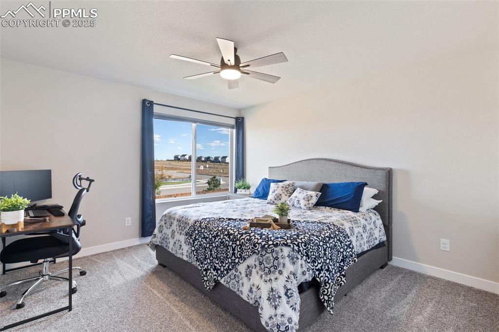 Image 17 of 26: Bedroom with light colored carpet, a desk, and ceiling fan