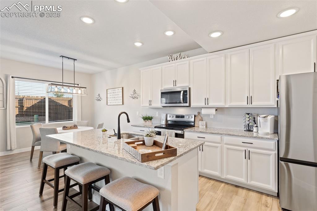 Image 7 of 26: Kitchen featuring stainless steel appliances, decorative light fixtures, wh
