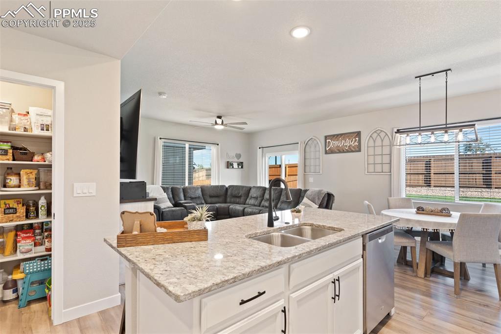 Image 9 of 26: Kitchen featuring white cabinets, light wood finished floors, light stone c