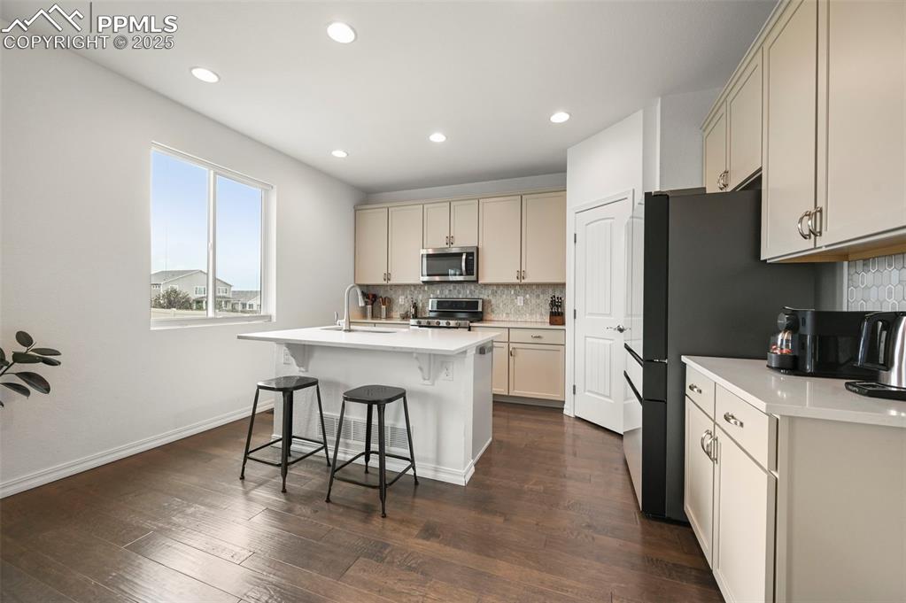 Image 10 of 50: Kitchen featuring stainless steel appliances, a kitchen breakfast bar, back