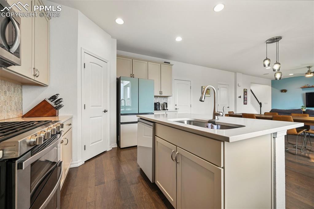 Image 13 of 50: Kitchen with stainless steel appliances, tasteful backsplash, light counter