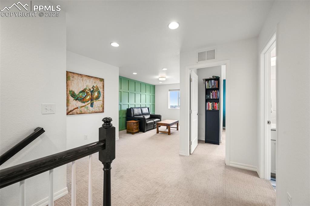 Image 14 of 50: Upstairs view of loft w/neutral colored carpet looking into bedroom 2