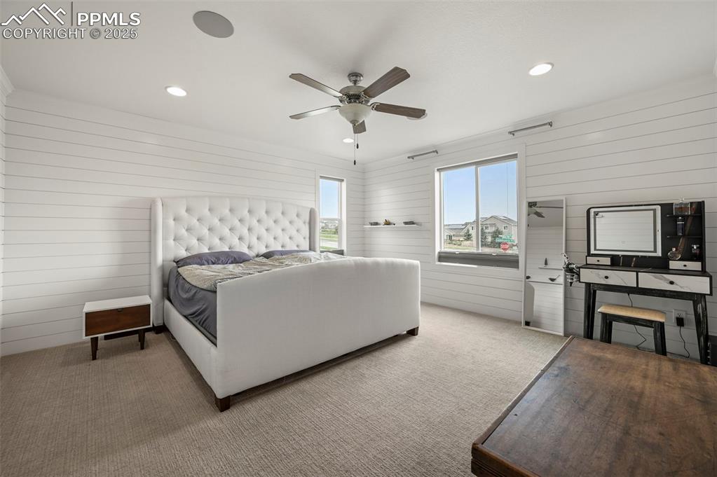 Image 17 of 50: Bedroom with neutral carpet, wooden walls, recessed lighting, and a ceiling