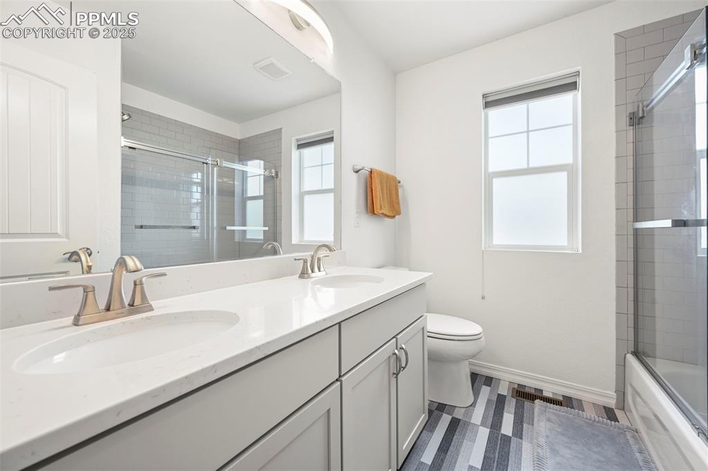 Image 26 of 50: Upper full bath with double vanity, healthy amount of natural light, and sh