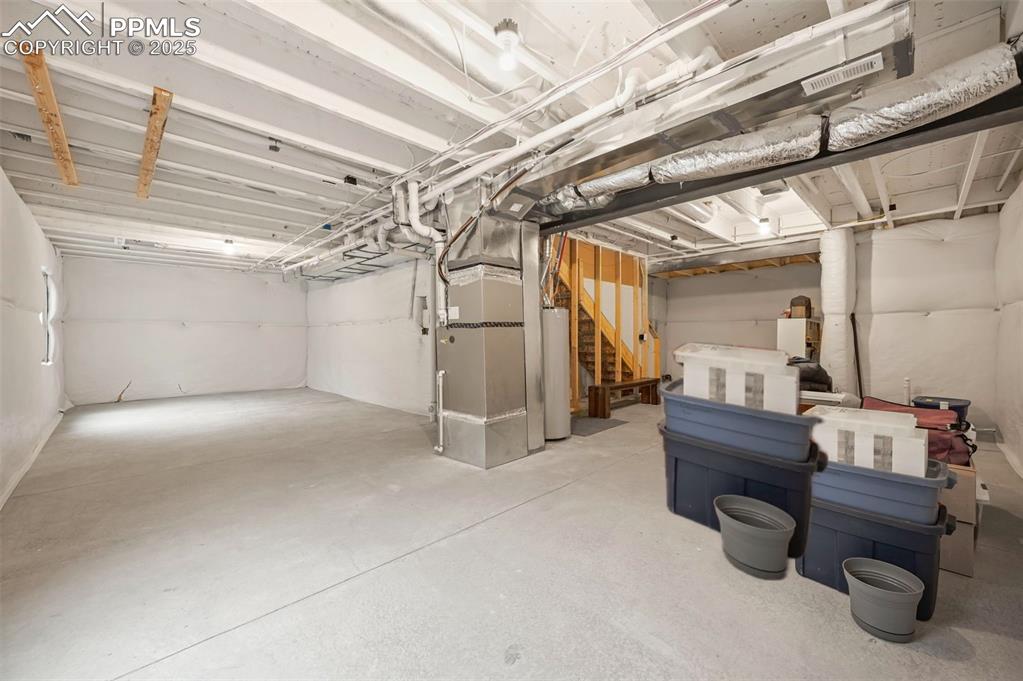 Image 44 of 50: Unfinished below grade area featuring gas water heater, stairway, and heati