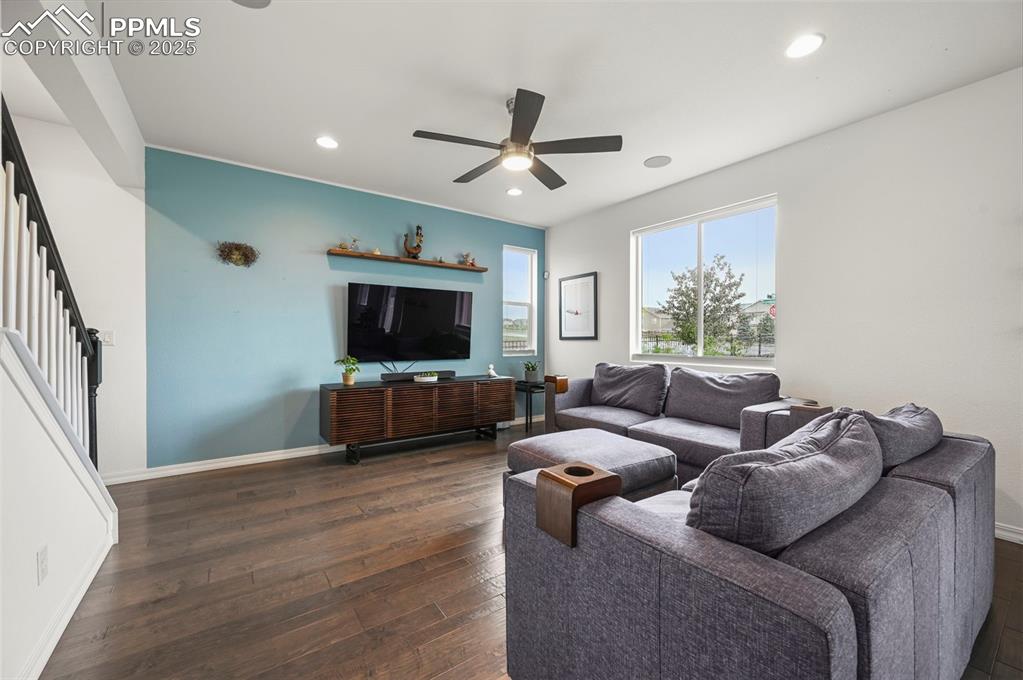 Image 6 of 50: Living area featuring stairs, ceiling fan, dark wood-type flooring, and rec