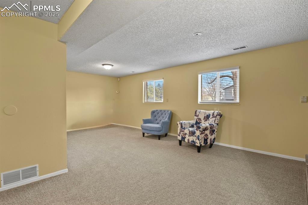 Image 14 of 17: Family room with a textured ceiling and carpet flooring