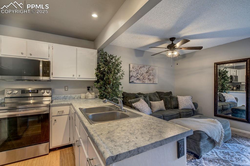 Image 10 of 48: Kitchen with stainless steel appliances, white cabinetry, open floor plan, 