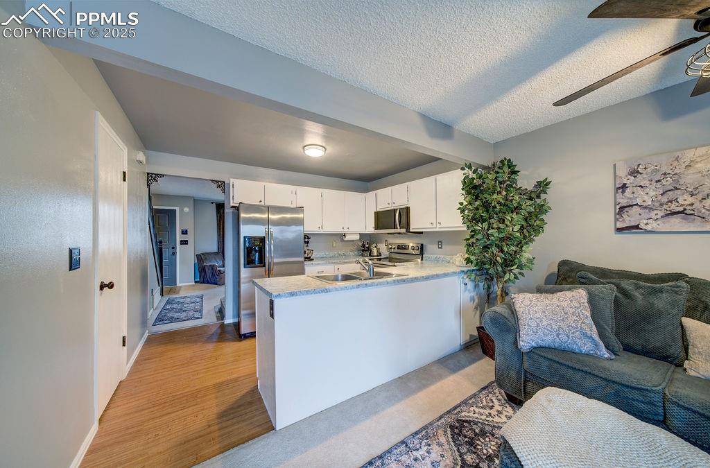 Image 14 of 48: Kitchen featuring white cabinetry, open floor plan, ceiling fan, stainless 